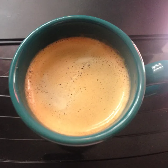 Xícara de cappuccino com espuma rosada sobre um pires branco, vapor suave subindo, tons quentes de rosa e creme